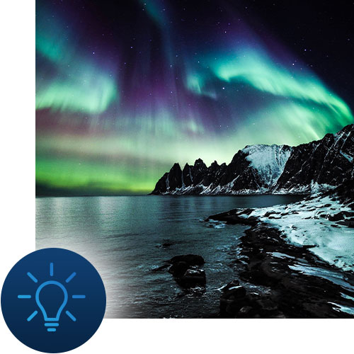 Northern lights over a rocky shoreline with lightbulb icon representing Tour Marketing Suite website development for your travel business.